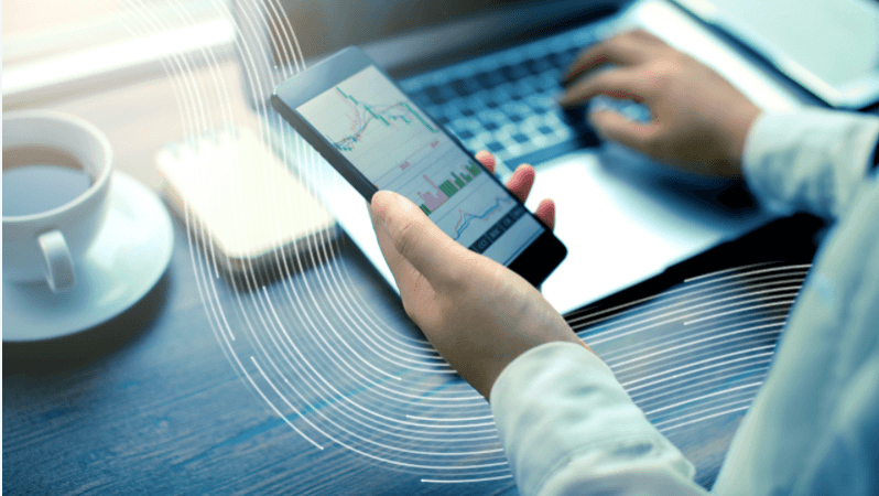 Person checking financial data on their phone and computer