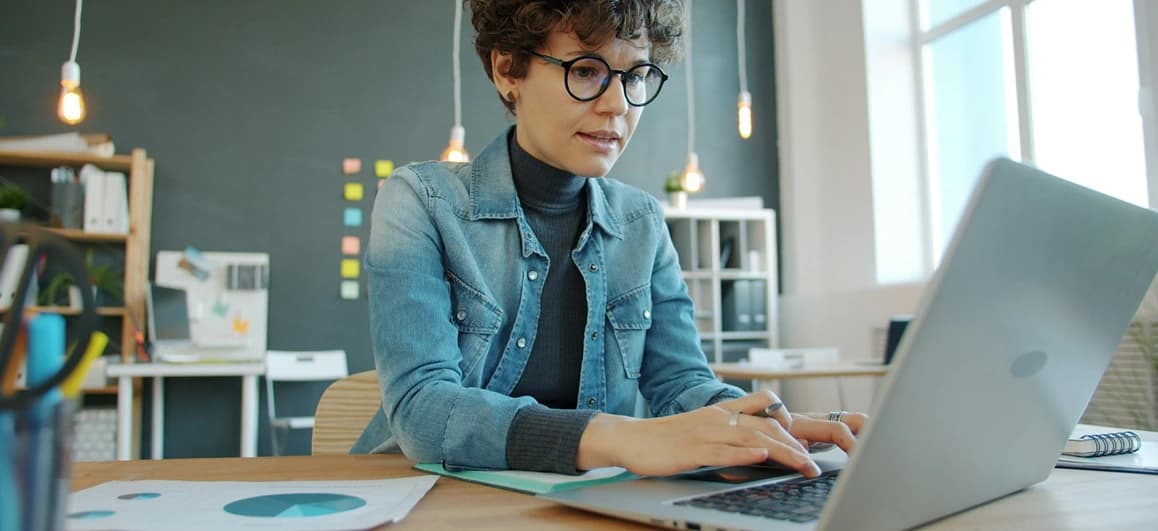 Person checking live currency exchange rates on a laptop while setting up an international money transfer, with simple currency symbols in the background.